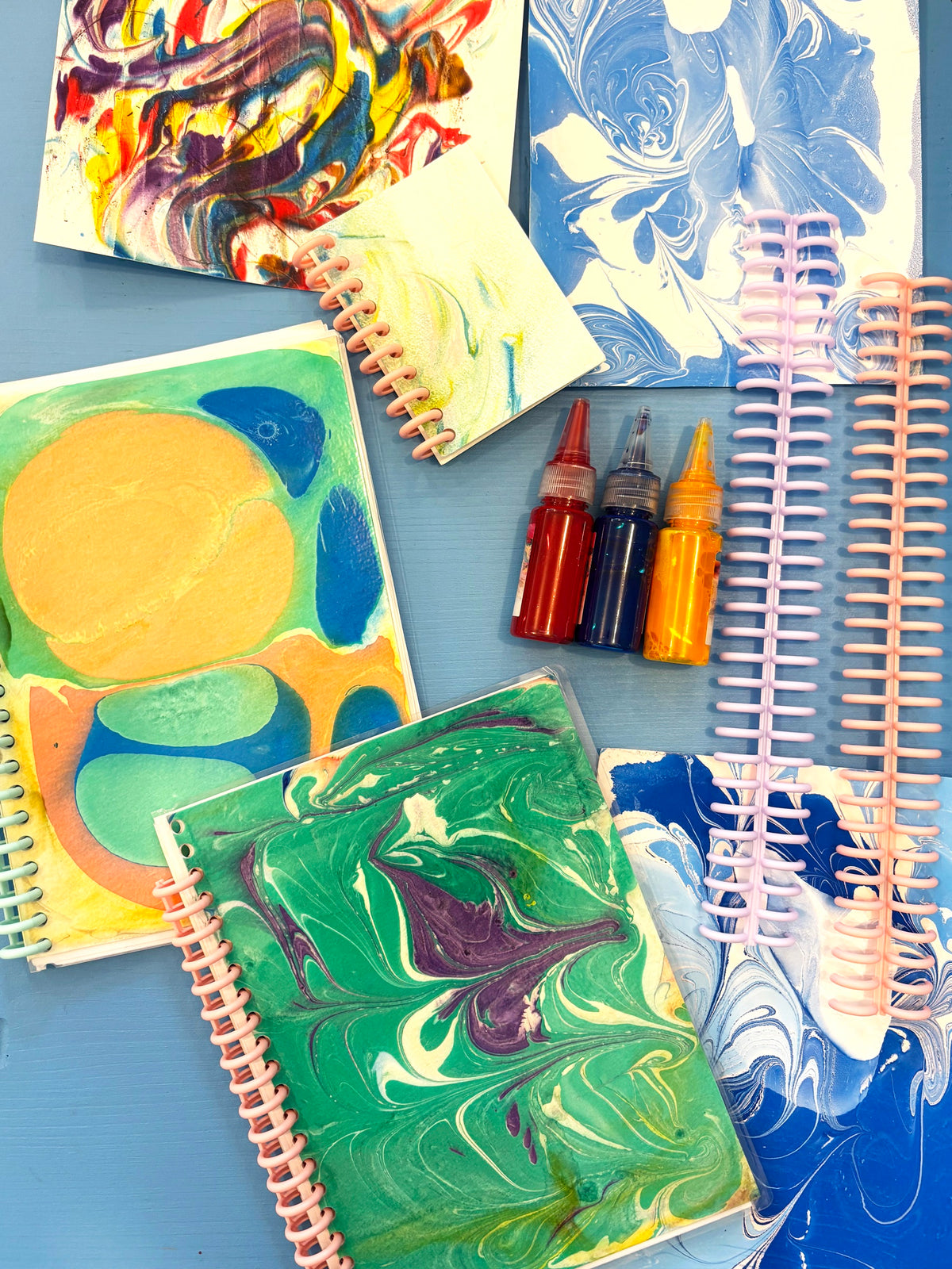 Carnets à spirale aux couvertures marbrées, encres colorées et feuilles de papier marbré